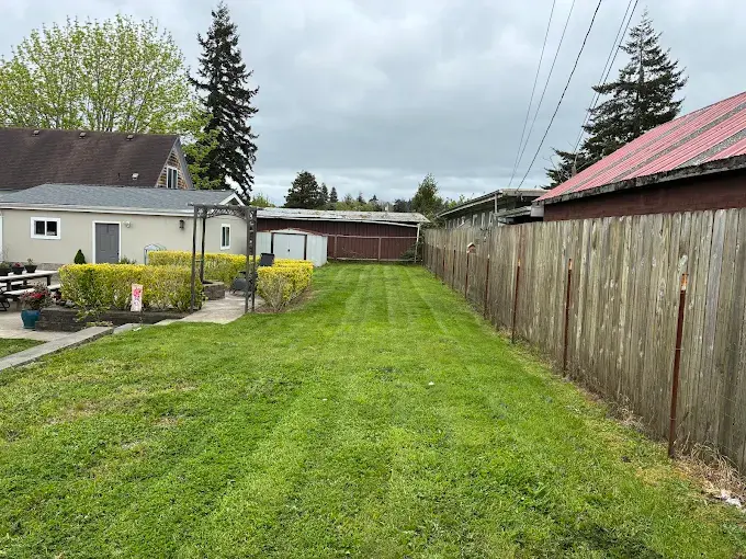Maintained backyard lawn with fenced perimeter and outbuildings in Coos County